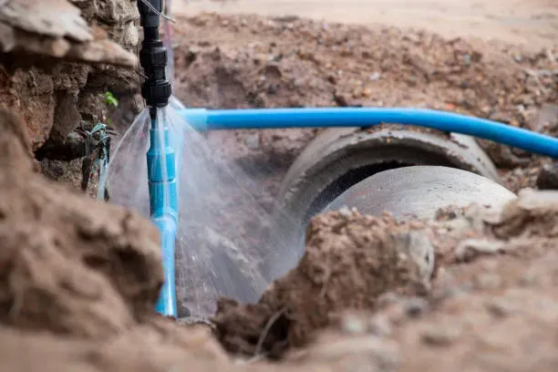 A plumber adjusting a water pipe system under a sink.