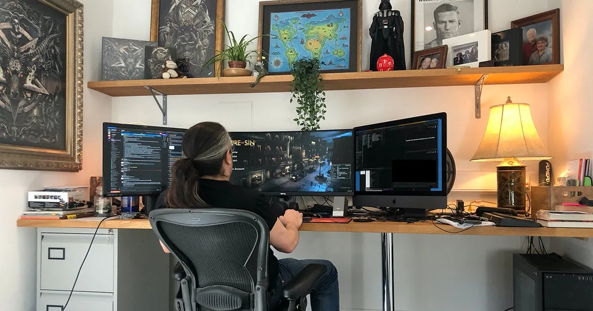 Organized desk setup displaying multiple monitors with real-time game development progress.