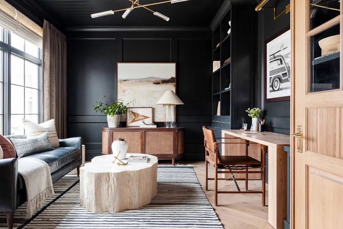 A chic home office featuring dark walls and warm wood tones that complement productivity and style.