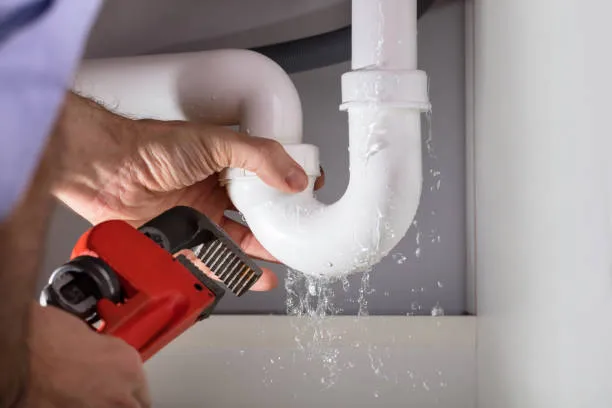 Using professional tools to tighten a valve on a water pipe.